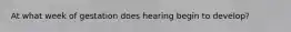 At what week of gestation does hearing begin to develop?