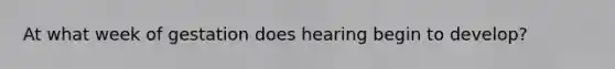 At what week of gestation does hearing begin to develop?