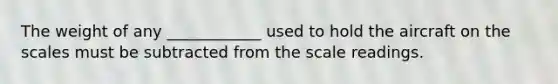 The weight of any ____________ used to hold the aircraft on the scales must be subtracted from the scale readings.