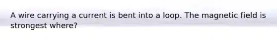 A wire carrying a current is bent into a loop. The magnetic field is strongest where?