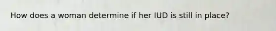 How does a woman determine if her IUD is still in place?