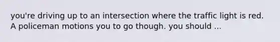 you're driving up to an intersection where the traffic light is red. A policeman motions you to go though. you should ...